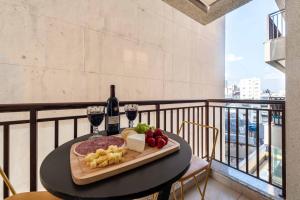 une table avec une assiette de fromage et de vin sur un balcon dans l'établissement Rover Centro, à São Paulo
