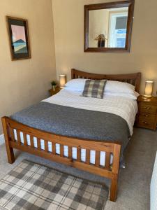 a bedroom with a bed and a mirror on the wall at Roy Place Gdn Apartment in Campbeltown