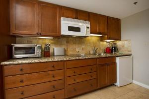 a kitchen with wooden cabinets and a microwave and refrigerator at Studio with gorgeous views tastefully furnished L1514 in Honolulu