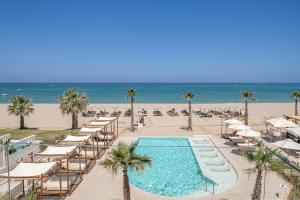 a swimming pool with lounge chairs and the beach at Iperion Beach Hotel in Rethymno