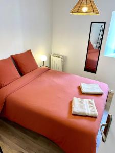a bedroom with a large orange bed with two towels at « Petit Paris » - T2 centre ville Parking/balcon in Albertville