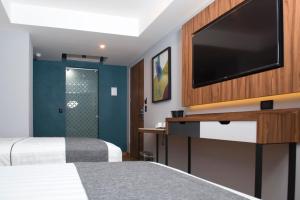 ein Hotelzimmer mit einem Bett und einem Flachbild-TV in der Unterkunft Hotel Flamencos in Mexiko-Stadt