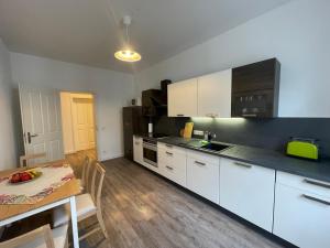 a kitchen with white cabinets and a table and a dining room at Ferienwohnung * Pension Luisengrün * Magenta TV Netflix 1Gb/s Internet WLAN/Wifi Waschmaschine in Chemnitz