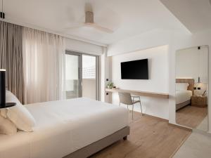 a white bedroom with a bed and a desk at Iperion Beach Hotel in Rethymno