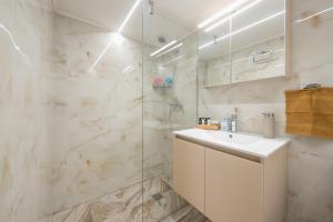 een badkamer met een witte wastafel en een douche bij Υπέροχο διαμέρισμα στο Ίλιον σύνορα με Πετρούπολη in Athene