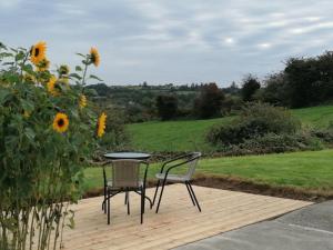 einen Tisch und Stühle auf einer Holzterrasse mit Sonnenblumen in der Unterkunft Radharc Na Greine in Cork