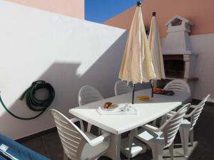 a white table with white chairs and an umbrella at Seacastle Residence Peniche in Atouguia da Baleia
