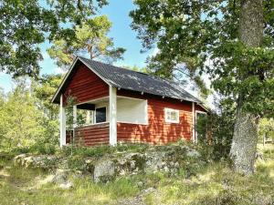 una pequeña cabaña roja en medio de un bosque en 8 person holiday home in VALDEMARSVIK, en Valdemarsvik