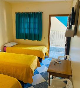 een kamer met 3 bedden, een tafel en een raam bij Pousada 277 in Foz do Iguaçu