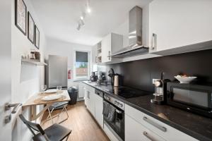 una cocina con electrodomésticos en blanco y negro y una mesa en Amalfi Apartments A01 - gemütliche 2 Zi-Wohnung mit Boxspringbetten und smart TV, en Kaiserslautern