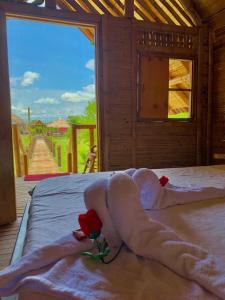 Una cama con toallas y dos rosas. en HOTEL CAMPESTRE LA ISLA en Villavieja