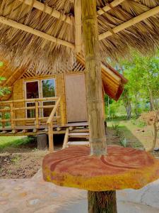 Cabaña de madera con banco y techo de paja en HOTEL CAMPESTRE LA ISLA, en Villavieja