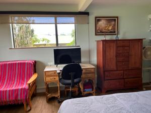 a bedroom with a desk with a computer and a bed at Waipio Studio Apartment in Kukuihaele