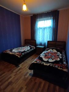 1 dormitorio con 2 camas y una ventana con cortina en Dito’s house en Katsʼkhi