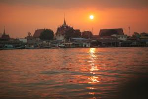 a sunset over a body of water with a group of buildings at Baan Tah On The Sea in Bang Sare +145 photos
