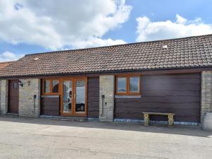 a detached house with a garage and a bench at The Barn in Baltonsborough