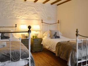 1 Schlafzimmer mit 2 Betten, 2 Lampen und einer Wand in der Unterkunft The Old Coach House in Woolfardisworthy