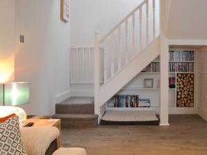 a living room with a staircase with bookshelves at Willow Cottage in Great Ryburgh