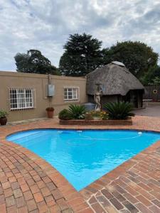 una gran piscina azul con un edificio con techo de paja en Sapphire Guest House en Germiston