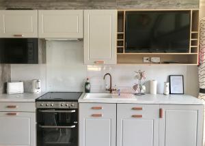 a kitchen with white cabinets and a sink and a stove at Torvean Holiday Park in Inverness