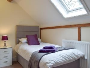 a bedroom with a bed with a purple pillow and a window at Yr Efail Argoed in Llandowror