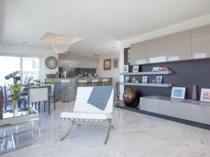 a living room with a white chair and a kitchen at The Penthouse - Clearview in Newquay
