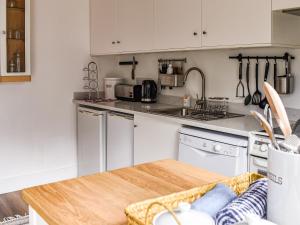 eine Küche mit weißen Schränken und einem Holztisch in der Unterkunft Farthing in Epsom