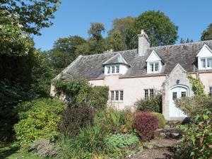 uma casa velha no meio de um jardim em Big Barns Cottage em Backies