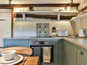 a kitchen with blue cabinets and a wooden table at Peppercorn Cottage in Cheriton