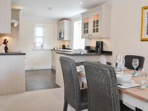 eine Küche mit einem Tisch und Stühlen sowie eine Küche mit weißen Schränken in der Unterkunft Grieves Cottage - Uk11107 in Montrose