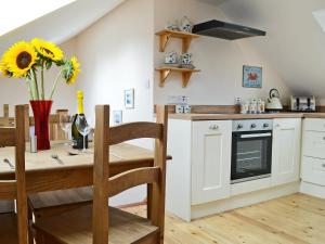 a kitchen and dining room with a table and chairs and a kitchen with white appliances at Stonechat Barn in Pancrasweek