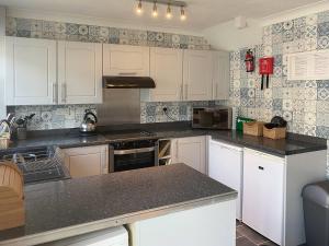 a kitchen with white cabinets and black counter tops at Seagull Cottage in Portreath