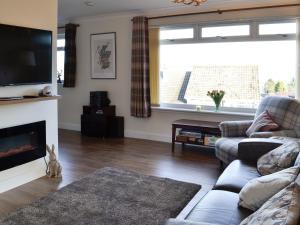 ein Wohnzimmer mit einem Sofa und einem TV in der Unterkunft Glencairn Rd, in Langbank