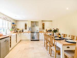 una cocina con armarios blancos y una mesa con sillas. en Limber Wold House en Great Limber