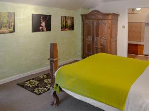 a bedroom with a yellow bed and a wooden cabinet at Caradon Apt - Cv14 in Saint Cleer