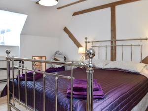 a bedroom with a metal bed with purple sheets at Holme Cottage in Eastry