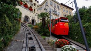 einem roten Zug auf einer Strecke vor einem Gebäude in der Unterkunft T21 Holiday in Bergamo