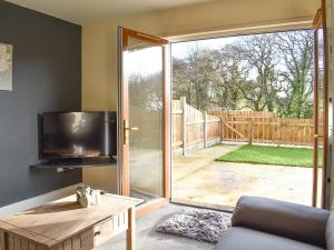 uma sala de estar com uma televisão e uma porta de vidro deslizante em One Dorchester Drive - Uk32037 em Inglewhite