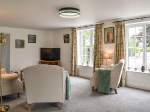 a living room with chairs and a tv and windows at Beacon Cottage in Ivegill