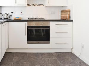 a kitchen with white cabinets and a stove at Avocet Cottage in Sheringham