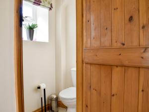 a bathroom with a toilet and a wooden door at Span Carr Cottage in Ashover