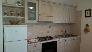 a kitchen with white cabinets and a white refrigerator at Agriturismo Le Giunchiglie in Alberese