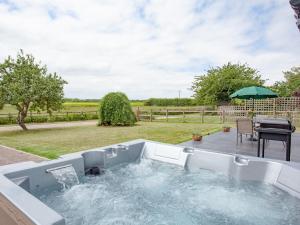 洛克斯頓的住宿－The Walled Garden，后院的热水浴池配有桌子和遮阳伞