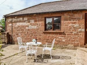 a table and chairs in front of a brick building at Low Moat in Canonbie