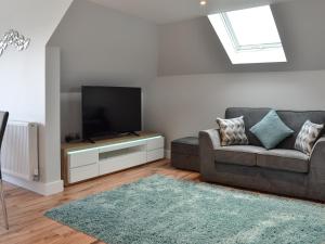 a living room with a couch and a flat screen tv at Penfose Apartment in Mevagissey
