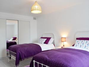 two beds in a room with purple blankets at Forvie View in Collieston