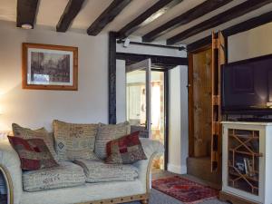 a living room with a couch and a tv at Rebeccas Cottage in Ashby Saint Ledgers