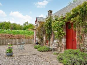 een huisje met een rode deur en een patio bij Rose Cottage in Blairgowrie
