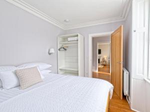 Dormitorio blanco con cama blanca y puerta en Lower Canterbury House en Gattonside