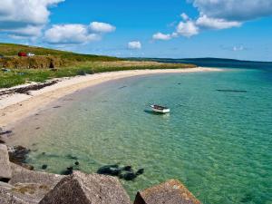 un barco en el agua junto a una playa en Fishermans Cove - W42425 en Pierowall